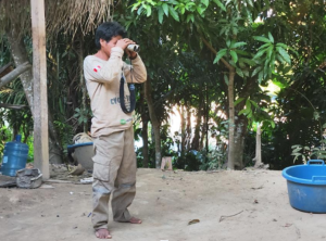 An Amazonian community member observes the forest with binoculars, participating in environmental monitoring and surveillance activities in his territory.  Photo: Jofre Torres